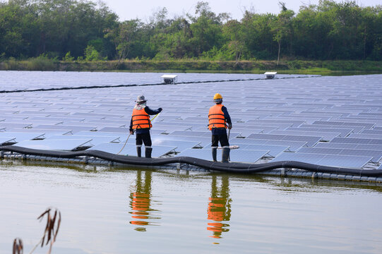 Workers are cleaning solar panels in a large body of water, a clean energy source for electricity generation.