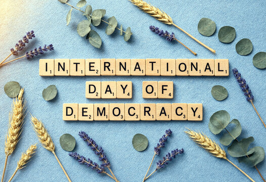 Wooden scrabble tiles spelling international day of democracy surrounded by lavender and wheat decorations