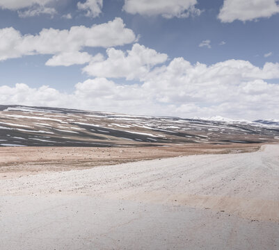 Dusty road of the Pamir Highway winds and twists in the valley of the Tien Shan mountains in Tajikistan in Pamir, landscape in the high desert mountains for background
