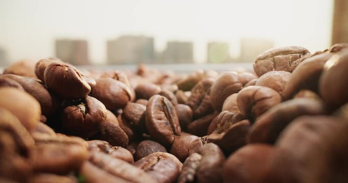 Slow motion coffee beans shifting on kitchen windowsill with city skyline in background.