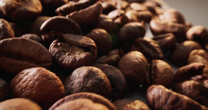 Slow motion closeup of roasted coffee beans shifting on tabletop in studio. tracking dolly push.