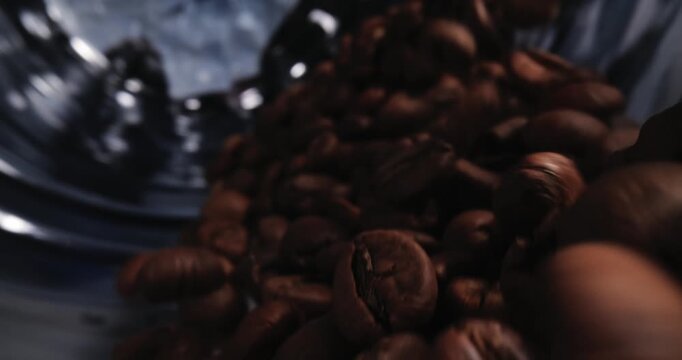 Slow motion close up of coffee beans tumbling inside roaster drum in industrial roastery, macro probe lens.