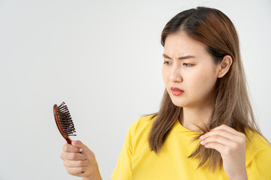 Asian woman very sad and upset looking at damaged hair, hair loss, hair thinning problem, vitamin deficiency, baldness, postpartum, biotin, zinc, menstrual or endocrine disorders, hormonal imbalance