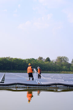 Workers are cleaning solar panels in a large body of water, a clean energy source for electricity generation.