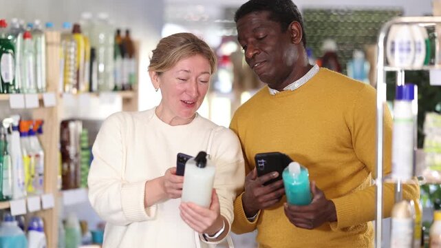 African man and European woman spouses store visitor scans QR code on packaging of shampoo or shower gel with phone, checks number of bonus points in customers profile. 