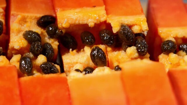 Close-up of ripe papaya flesh and glossy black seeds, showcasing the vibrant orange color and natural texture of this tropical fruit. Rich in vitamins, antioxidants, and dietary fiber, the image is id