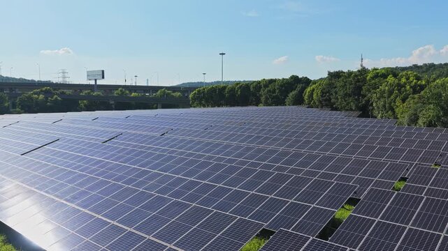 Drone gliding above solar panels with forest on the horizon