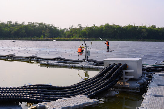 Workers are cleaning solar panels in a large body of water, a clean energy source for electricity generation.
