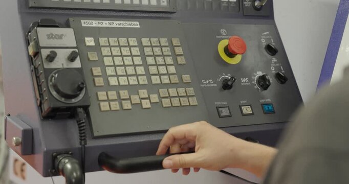 CNC machine operator using the control panel to operate and program a CNC machine, demonstrating industrial automation, precision manufacturing, and machining.