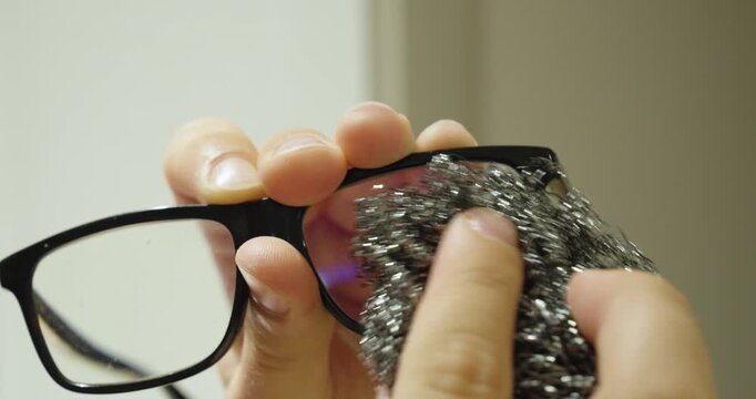 Close-up of a person incorrectly cleaning eyeglass lenses with abrasive steel wool, illustrating improper lens care, scratches, and damaged eyewear.