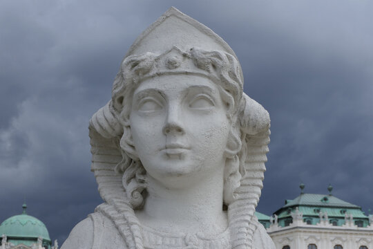 Baroque Sphinx Statue in Front of Upper Belvedere Palace Under Dramatic Storm Clouds in Vienna. 