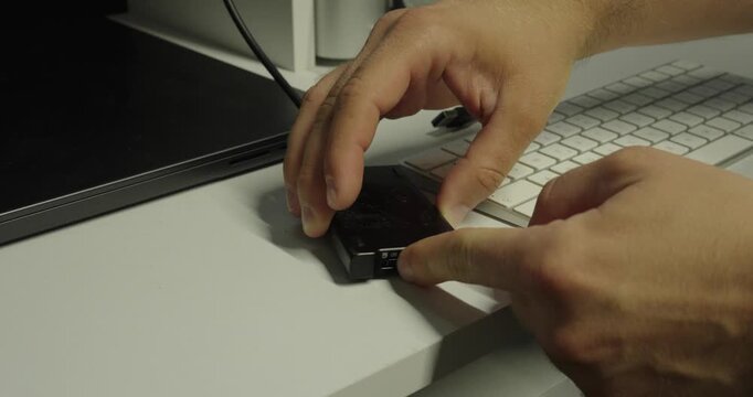 Close-up of a person inserting and removing a memory card from a USB card reader connected to a computer.