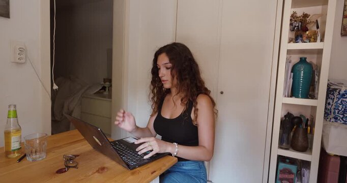 A stressed woman struggles with problems while working on her laptop at home.