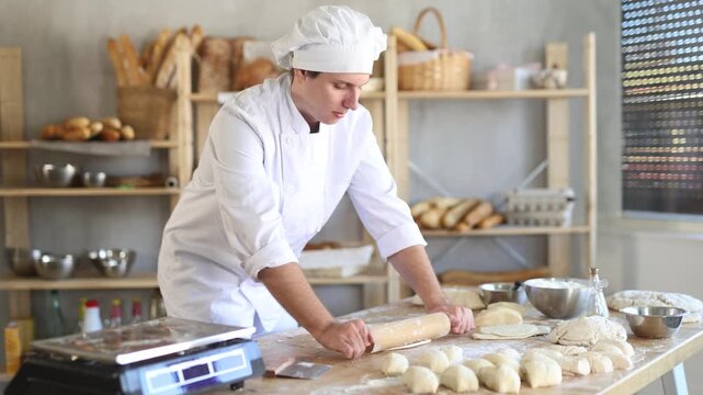 Bakery worker, young baker, rolls out raw yeast dough with a rolling pin
