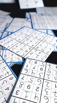 Close up view of handwritten solved sudoku puzzle cards randomly arranged on a black studio background, showcasing the concept of logic, problem solving, and intellectual challenges