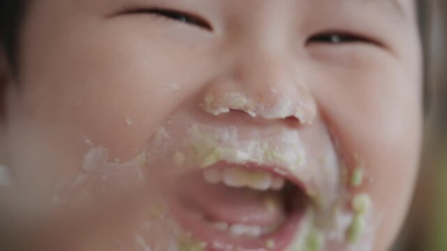Asian baby boy self feeding sweet corn using baby led weaning method at home.