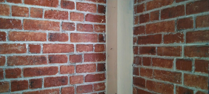 Rustic red brick wall corner with vertical support columns.