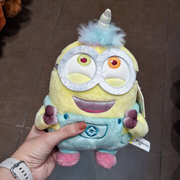 Hand Holding Cute Plush Minion Doll Wearing Fluffy Unicorn Costume on April 22, 2026 in Bangkok, Thailand 
