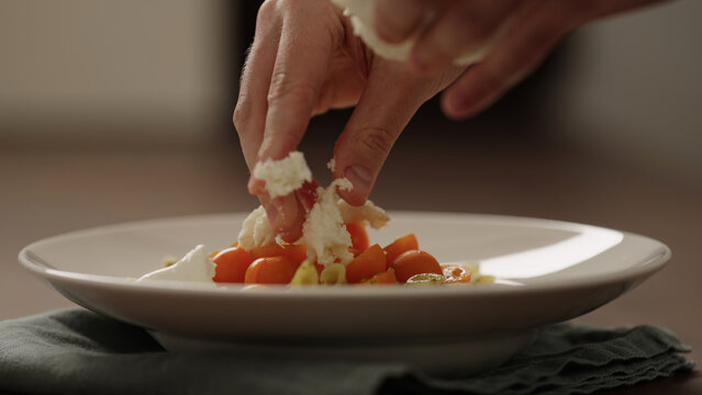 making pesto penne pasta with mozzarella and tomatoes in deep plate closeup