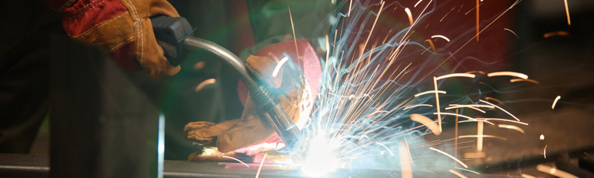 Welder working on metal fabrication in industrial workshop. Image suitable for manufacturing training programs and vocational school marketing, close up shot