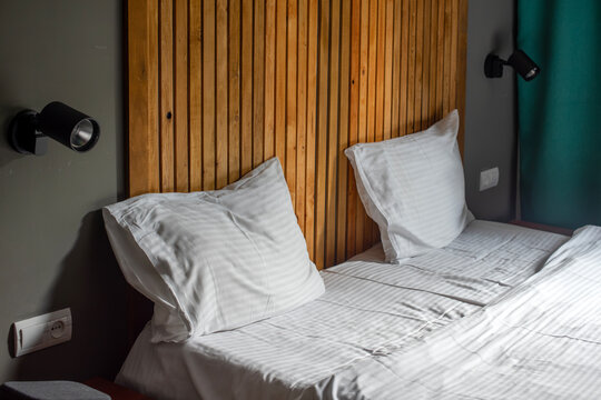 Neatly made double bed with white pillows and wooden headboard in a modern hotel room interior
