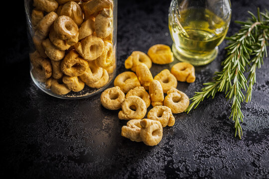 Italian Taralli Crackers With Olive Oil and Rosemary in a Glass Jar on Dark Surface