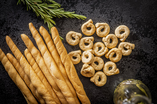 Rustic Italian Breadsticks and Taralli With Rosemary and Olive Oil on Dark Slate