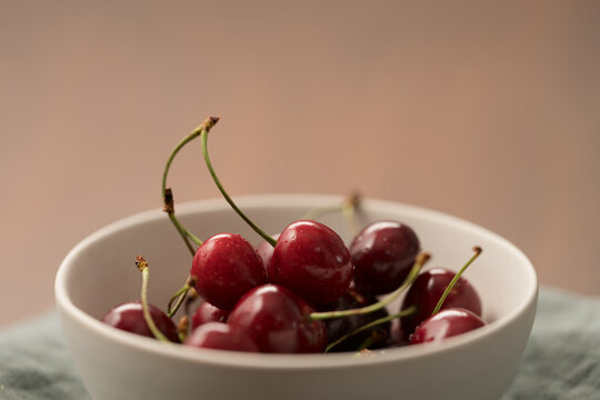 ripe cherries in white ceramic bowl on linen napkin