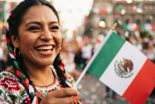 Mexican woman smiling and holding national flag during Independence Day street celebration.