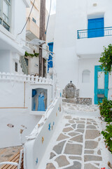 Fototapeta premium Charming narrow street in Naxos, Greece with whitewashed buildings and blue accents