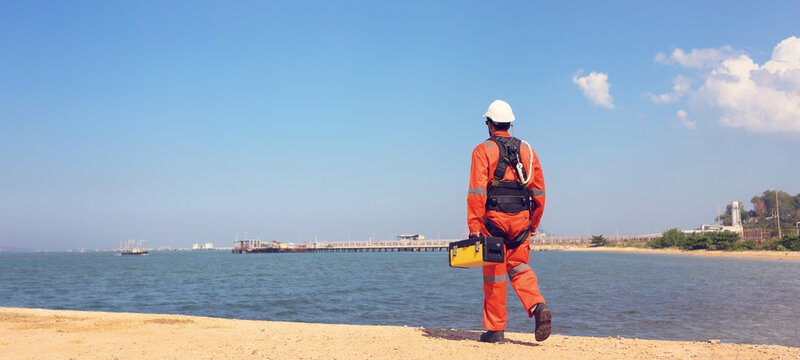 Male chemical engineer doing inspection work at a chemical storage tank on the seaside.	