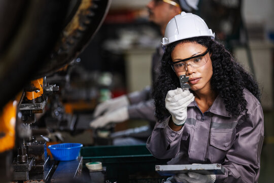 Female Quality Control Technician Inspecting Precision Metal Component in Modern Manufacturing Factory