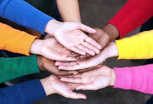 Diverse group of people stacking hands together in unity and teamwork showing support and collaboration