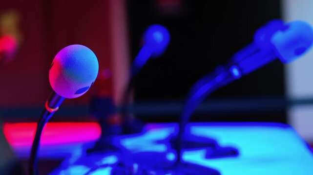 Modern professional conference microphones setup in studio with neon lighting.