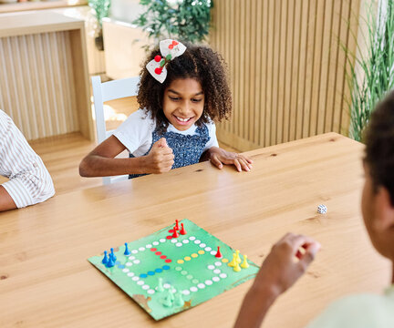 Portrait of a happy african american family at home, having fun playing a board game challenge game, playing board game ludo at home