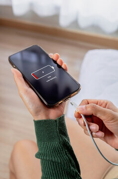 Close-up of a person charging a smartphone with low battery using a USB cable. Concept of mobile power, battery charging, technology and portable devices.