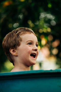 Close Up Portrait of Happy Little Boy Looking Up and Smiling Outdoors