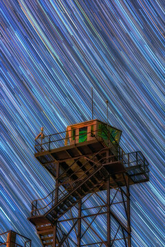 Star trails over watchtower in night sky long exposure photography