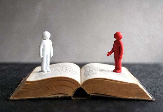 Two colorful figurines standing on an open book symbolizing communication and discussion concepts in a creative way