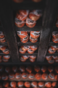 Daruma Dolls Viewed From Below on Dark Wooden Shelf