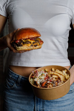 Woman holding a double cheeseburger and a food bowl