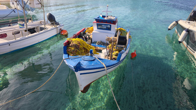 Charming fishing boat anchored in clear waters of Agios Arsenios, Naxos, Greece