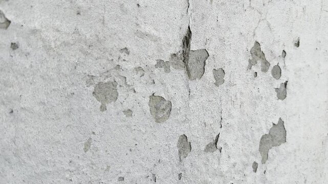 Textured concrete wall surface showing weathered damage with peeling paint in motion as a high quality abstract video clip animation