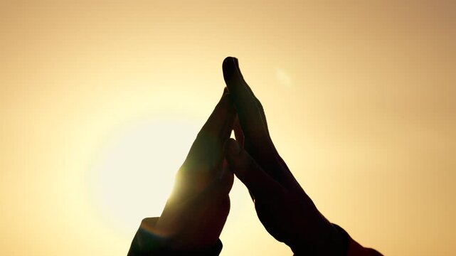 Hand silhouette meets partner hand at sunset. Strong teamwork shows through direct touch. People seem happy sharing greeting. Partners feel calm at sunset. Light makes warm teamwork silhouette.