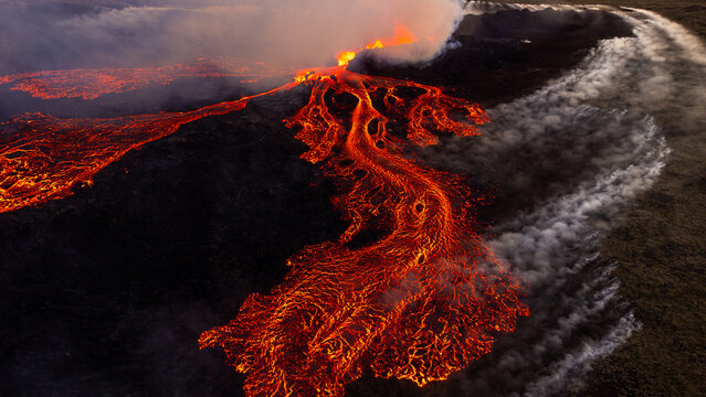 Aerial view of the Litli-Hrutur volcanic eruption with glowing lava flows spreading across the dark volcanic landscape in Grindavik, Grindavikurbaer, Iceland.
