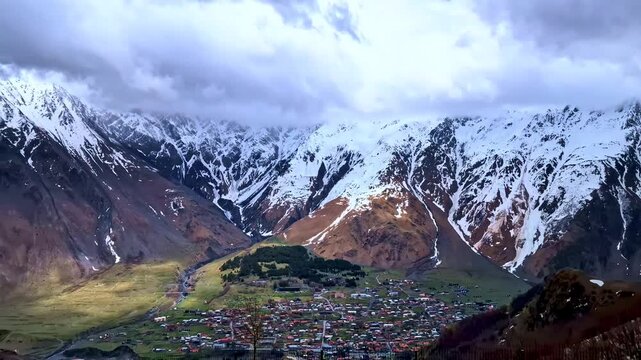 Stepantsminda town beneath snowy Caucasus mountains in Georgia