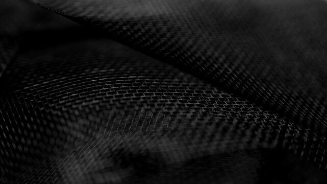 Abstract texture of black plastic mesh with woven pattern forming flowing folds and geometric structure. Synthetic material. Macro