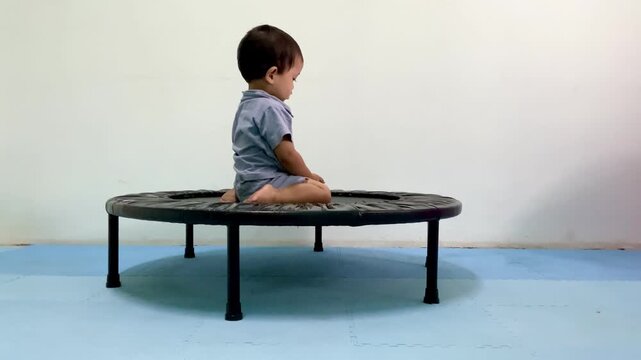 Toodler performing physical therapy exercises on a mini trampoline for motor skill development