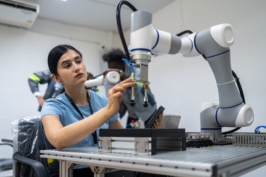 Robotic Collaboration in Innovation: A focused engineer works alongside a sophisticated robotic arm on a complex task.