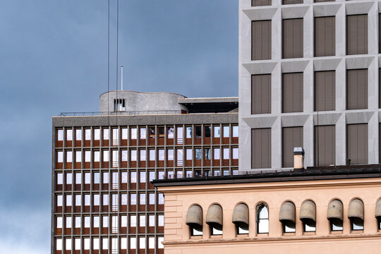Beneath an open sky, a peach facade holds the foreground in Oslo, Norway, while historic architecture meets layered modern buildings in quiet contrast.